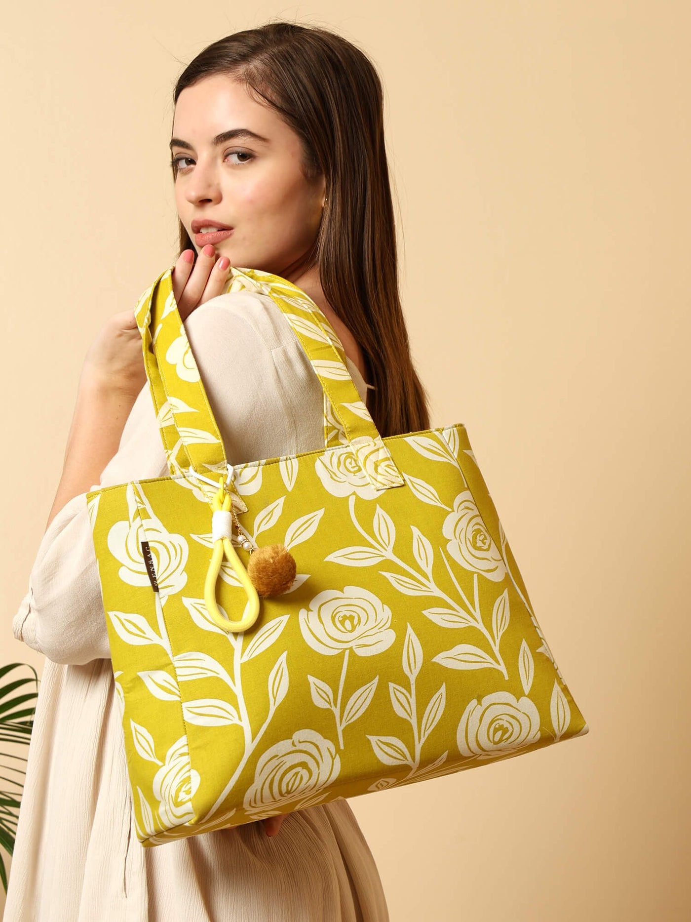 Woman holding a yellow tote bag with floral pattern on a beige background  by ENSAC