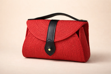 Red woven handbag with black leather strap on a beige background BY ENSAC