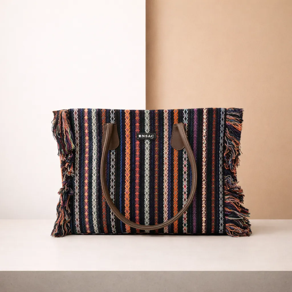 Striped handbag with fringes on a white surface against a beige background BY ENSAC