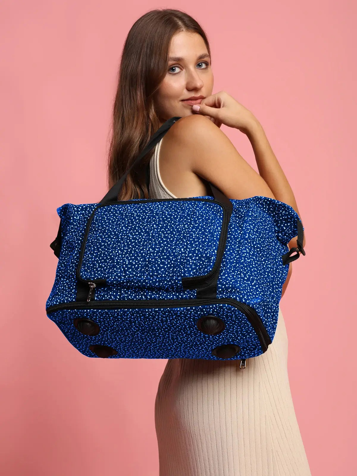 Woman carrying a blue polka dot bag against a pink background by Ensac